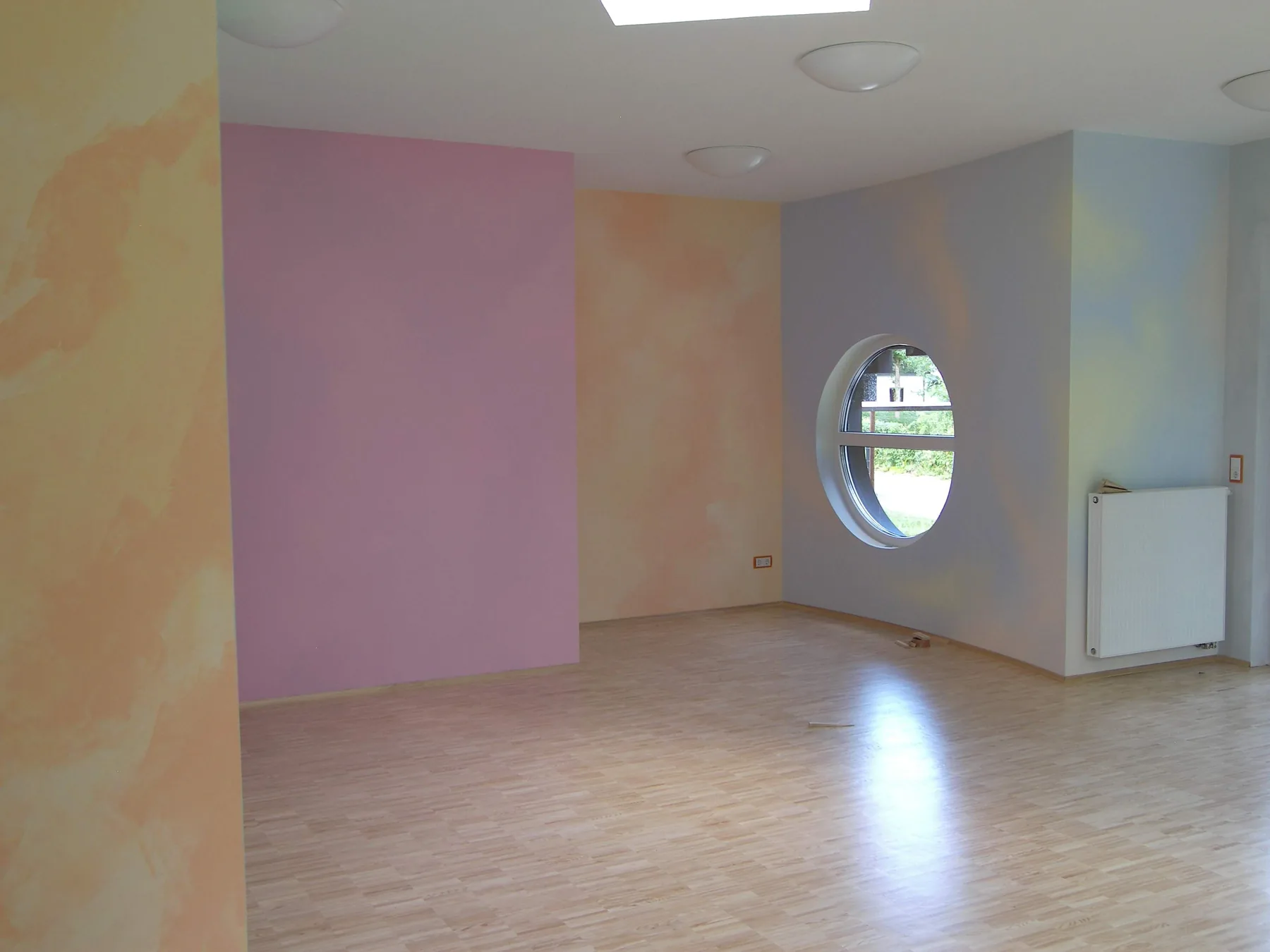 Pastellfarbig gestalteter Raum mit rundem Fenster