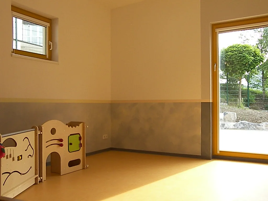 Kindergartenraum in warmen Gelb- und Grautönen