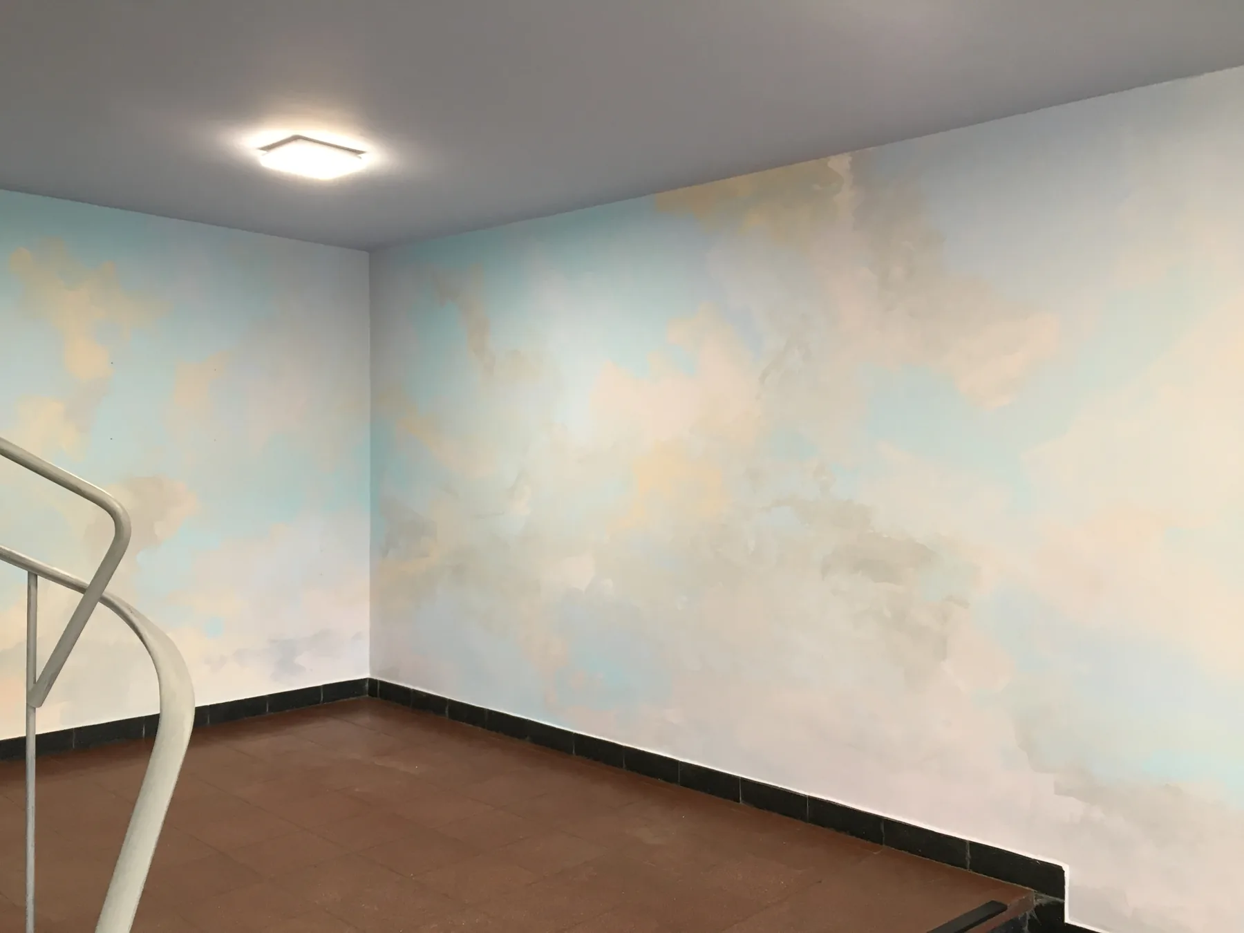Treppenraum mit Wandgestaltung in Blau und warmen Pastelltönen