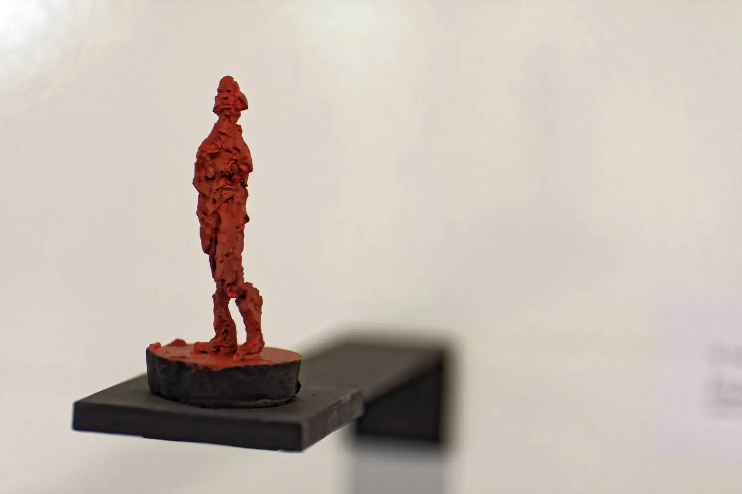 Kleine rote figürliche Skulptur auf schwarzem Sockel