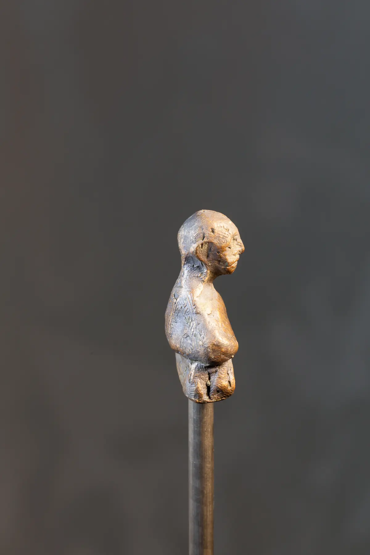 Kleine figürliche Arbeit auf einem Stab vor dunklem Hintergrund