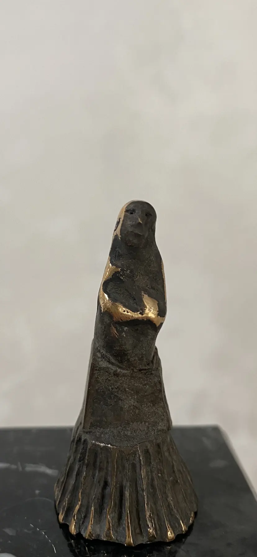 Dunkle kleine Figur auf schwarzem Sockel