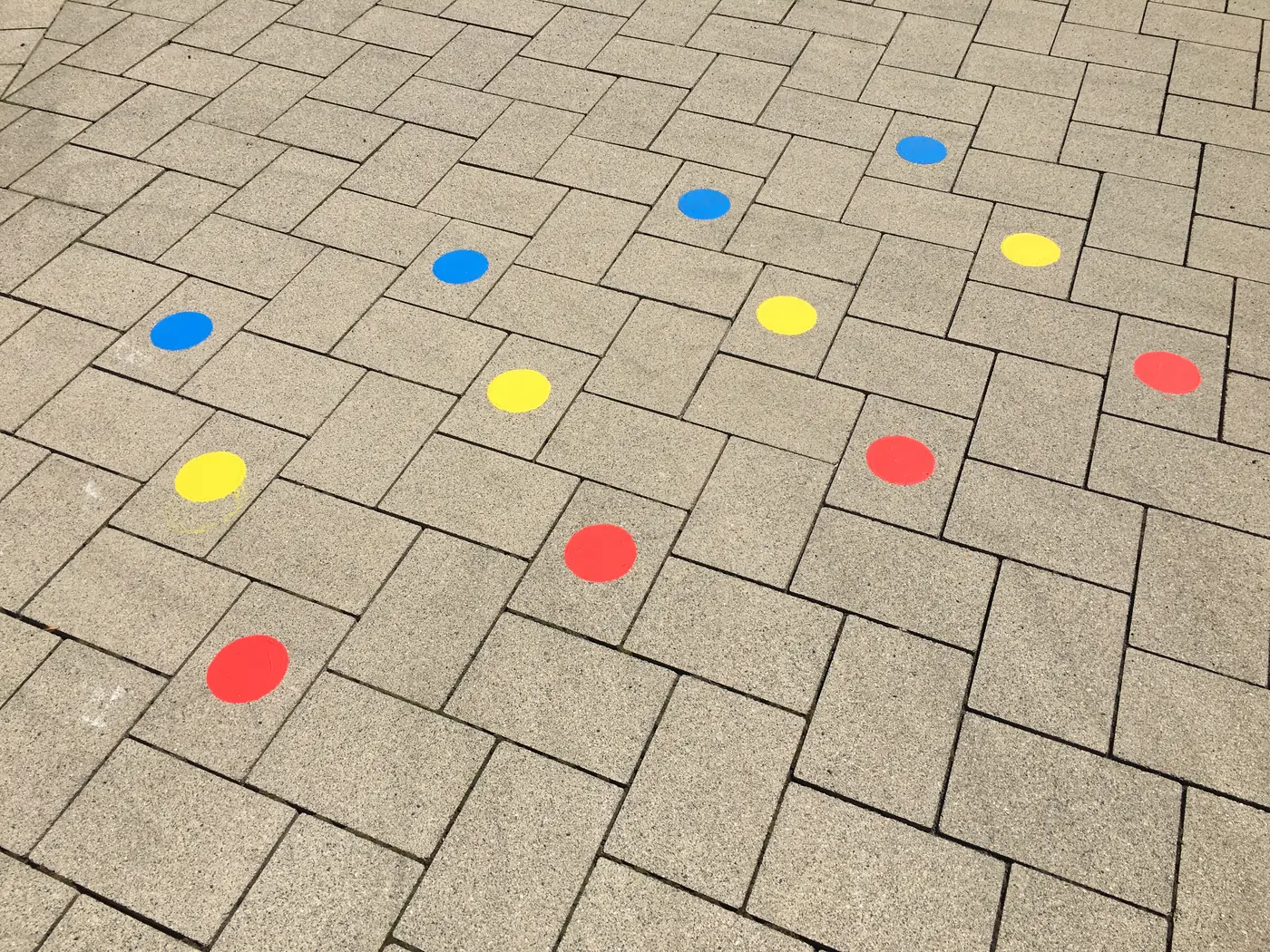 Rote, gelbe und blaue Spielpunkte auf Pflastersteinen