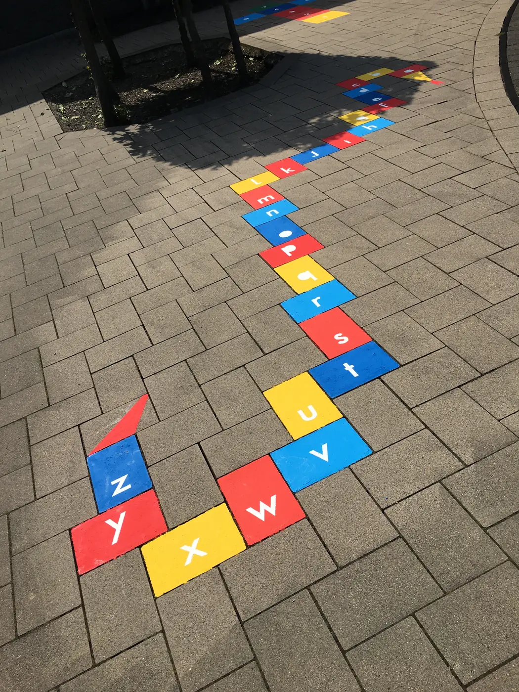 Gewinkeltes Buchstaben- und Zahlenspiel auf Pflastersteinen